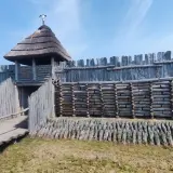 Drewniany gród obronny, przypominający rekonstrukcję osady z epoki brązu, z charakterystyczną wieżą i palisadą. To właśnie tutaj znajduje się Janowiec Wielkopolski.