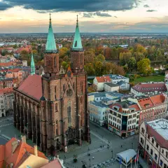 Widok z lotu ptaka na miasto nad Kaczawą. Dominują ceglana katedra z zielonymi wieżami i kolorowe kamienice.