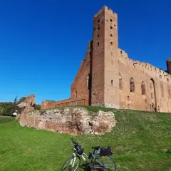 Ruiny zamku w Grudziądzu na tle błękitnego nieba. Rower z sakwami czeka na dalszą podróż.