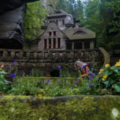 Kamienny domek w otoczeniu skał i zieleni, idealne miejsce na wędrówkę po czeska szwajcaria szlaki.