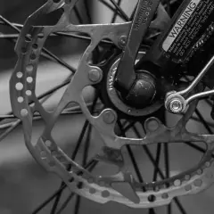 Tarcza hamulcowa i szprychy roweru. Widoczny mechanizm przerzutek Shimano i ostrzeżenie.