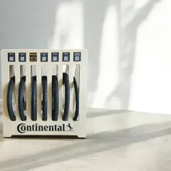 Stojak z oponami rowerowymi Continental. Różne modele opon, każdy z etykietą i kodem QR, prezentują bogactwo rozmiarów opon rowerowych.