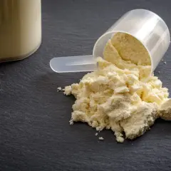 Miarka z proszkiem kazeiny micelarnej obok szklanki z napojem.