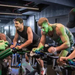 Intensywny trening spinningowy. Ludzie na rowerach stacjonarnych, skupieni na wysiłku.
