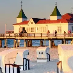 Plaża w Ahlbecku z molo i białymi koszami plażowymi. To popularne atrakcje nad Bałtykiem.