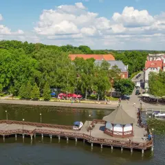 Malownicze mazury miejscowości nad jeziorem, z drewnianym molo, altaną i urokliwą zabudową.