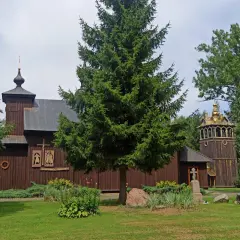 Drewniana cerkiew w Terespolu z dzwonnicą i krzyżami na cmentarzu.