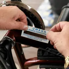 Ręce przyklejają naklejkę z napisem "Uwaga Rower Oznakowa" na ramę roweru. To część programu znakowanie rowerów w Rzeszowie.