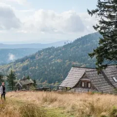 Dziewczyna na tle malowniczych gór Dolnego Śląska. Drewniane chaty i lasy tworzą sielski krajobraz.