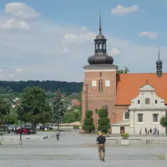 Włocławek atrakcje na weekend: plac z katedrą, zielone drzewa i ludzie spacerujący w słoneczny dzień.