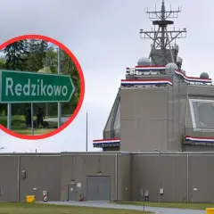 Tablica z napisem "Redzikowo" obok nowoczesnej instalacji wojskowej.