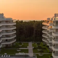Nowoczesne apartamenty w Rogowie z widokiem na las i morze. Zachód słońca maluje niebo na pomarańczowo.