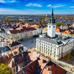 Widok na rynek z ratuszem i wieżą zegarową w najstarszym mieście w Polsce. Dachy kamienic tworzą malowniczy krajobraz.