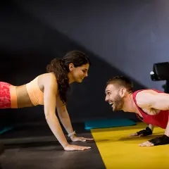 Para i mężczyzna ćwiczą pompki w siłowni. Różne rodzaje pompek to świetny trening całego ciała.