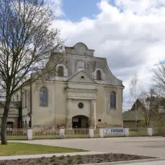 Synagoga w Orli zaprasza. Stary budynek z charakterystycznym dachem i oknami, otoczony płotem i drzewami.