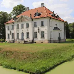 Pałac w Choroszczy otoczony fosą i zielenią. Drewniany mostek prowadzi do rezydencji.