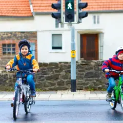 Dwóch chłopców na rowerach czeka na zielone światło. Czy karta rowerowa jest obowiązkowa? Bezpieczeństwo przede wszystkim!