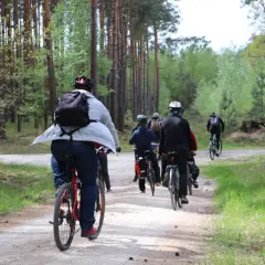 Grupa rowerzystów przemierza leśną ścieżkę. Każdy pedałujący spala kalorie, ciesząc się aktywnością na świeżym powietrzu.