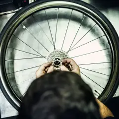 Ręce mechanika składają kasetę z zębatkami, przygotowując wolnobieg do montażu na kole rowerowym.