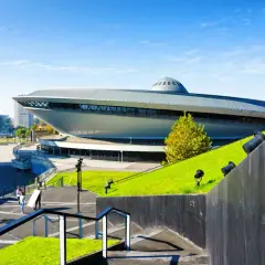Spodek w Katowicach, ikona województwa śląskiego, otoczony zielenią i nowoczesną architekturą.