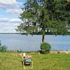 Osoba czyta książkę na leżaku nad jeziorem. To jedno z magicznych miejsc Kujawsko-Pomorskiego.