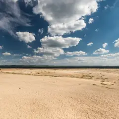 Pustynia Błędowska pod błękitnym niebem z chmurami. Sprawdź pustynia błędowska cennik atrakcji.