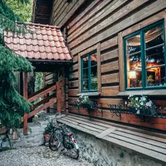 Drewniana chata z kwiatami w oknach i rowerem przy schodach. Idealne romantyczne miejsca Dolny Śląsk na wypoczynek.