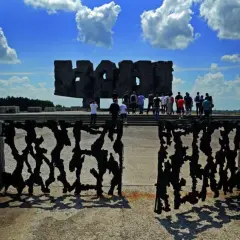 Brama pamięci na terenie byłego obozu Majdanek. Grupa ludzi zwiedza miejsce pamięci.
