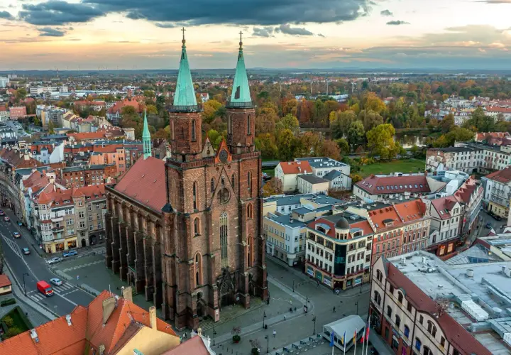 Widok z lotu ptaka na miasto nad Kaczawą. Dominują ceglana katedra z zielonymi wieżami i kolorowe kamienice.