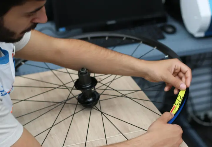 Mechanik sprawdza rozmiar koła rowerowego 27.5 cala. Sprawdź decathlon serwis rowerowy cennik dla usług.