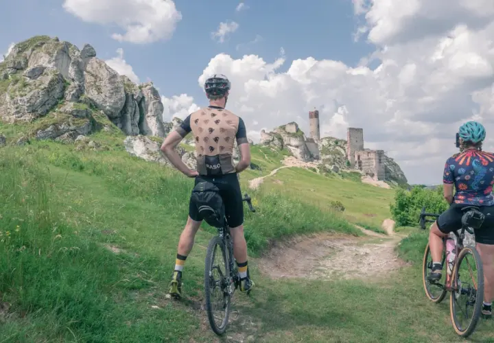 Dwaj rowerzyści podziwiają ruiny zamku na szlaku rowerowym Orlich Gniazd.