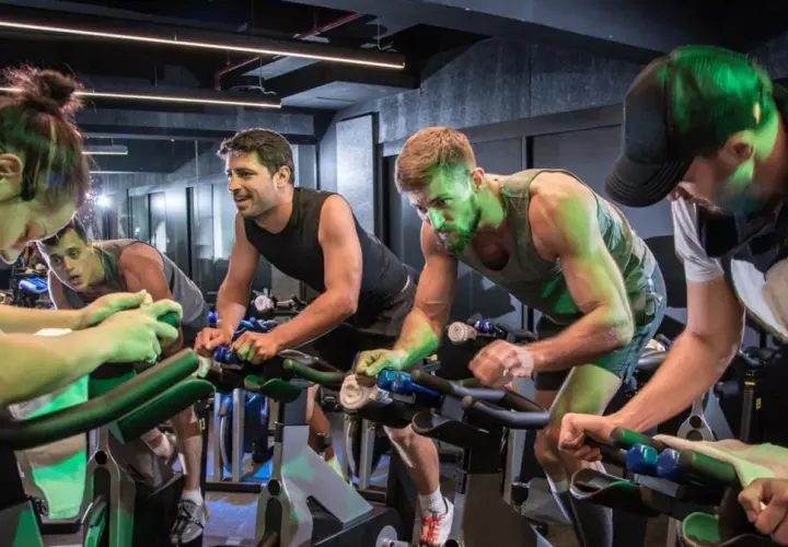 Intensywny trening spinningowy. Ludzie na rowerach stacjonarnych, skupieni na wysiłku.