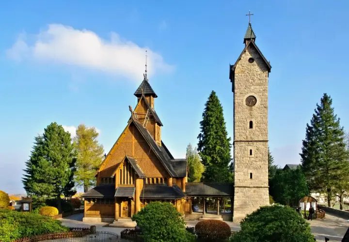 Drewniany kościółek i kamienna wieża z zegarem. Idealne miejsce na spokojny weekend w Karpaczu.