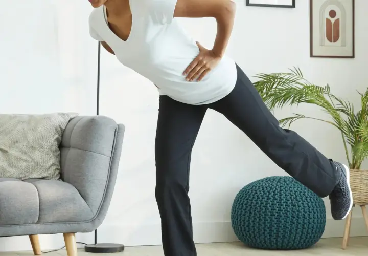 Kobieta w ciąży ćwiczy pilates, unosząc nogę. Dba o formę i dobre samopoczucie.