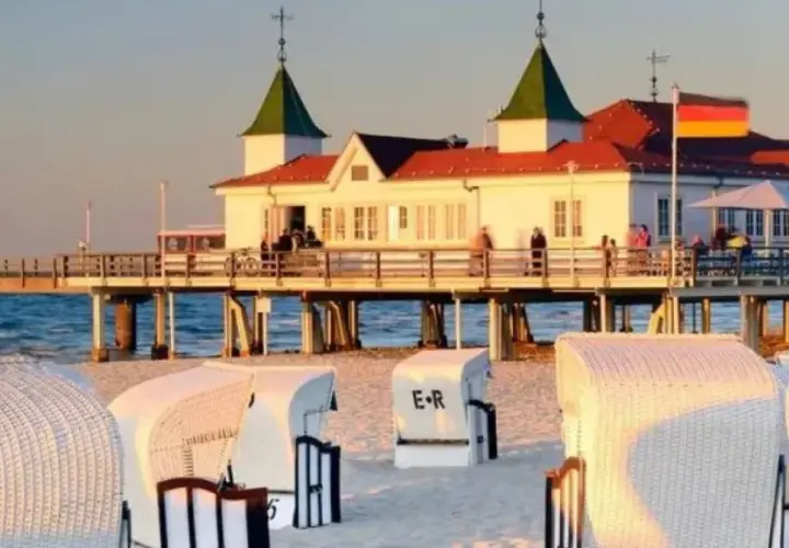 Plaża w Ahlbecku z molo i białymi koszami plażowymi. To popularne atrakcje nad Bałtykiem.