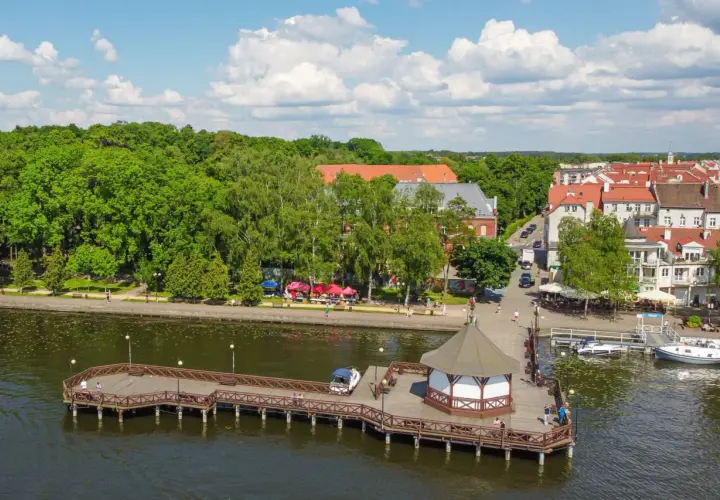 Malownicze mazury miejscowości nad jeziorem, z drewnianym molo, altaną i urokliwą zabudową.