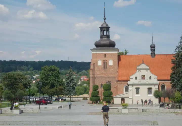 Włocławek atrakcje na weekend: plac z katedrą, zielone drzewa i ludzie spacerujący w słoneczny dzień.