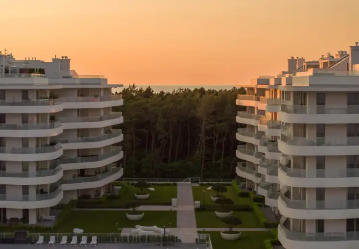 Nowoczesne apartamenty w Rogowie z widokiem na las i morze. Zachód słońca maluje niebo na pomarańczowo.