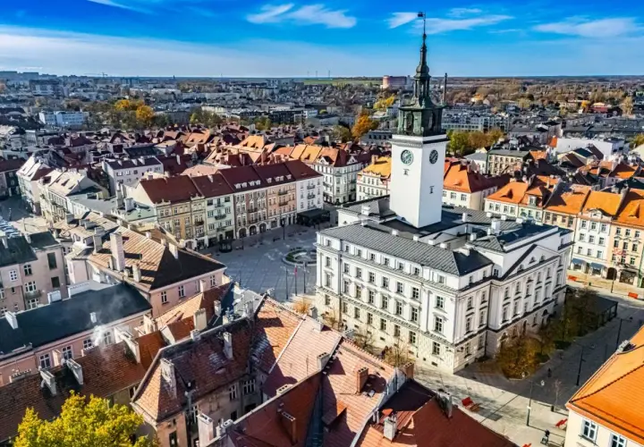 Widok na rynek z ratuszem i wieżą zegarową w najstarszym mieście w Polsce. Dachy kamienic tworzą malowniczy krajobraz.