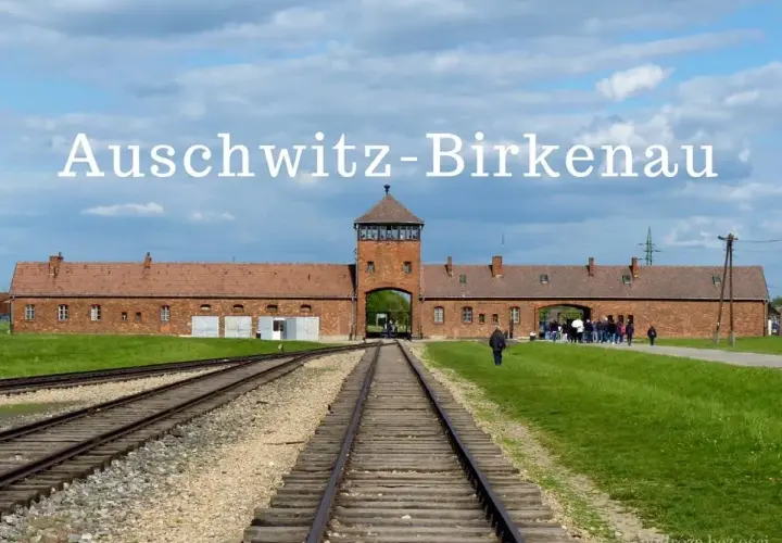 Brama obozowa Auschwitz-Birkenau, gdzie historia przypomina o tragedii. Tłum zwiedzających podąża torami.