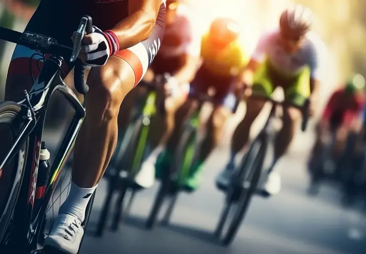 Wyścig **bikery** w pełnym słońcu. Kolarze w aerodynamicznych strojach pędzą po trasie, skupieni na rywalizacji.