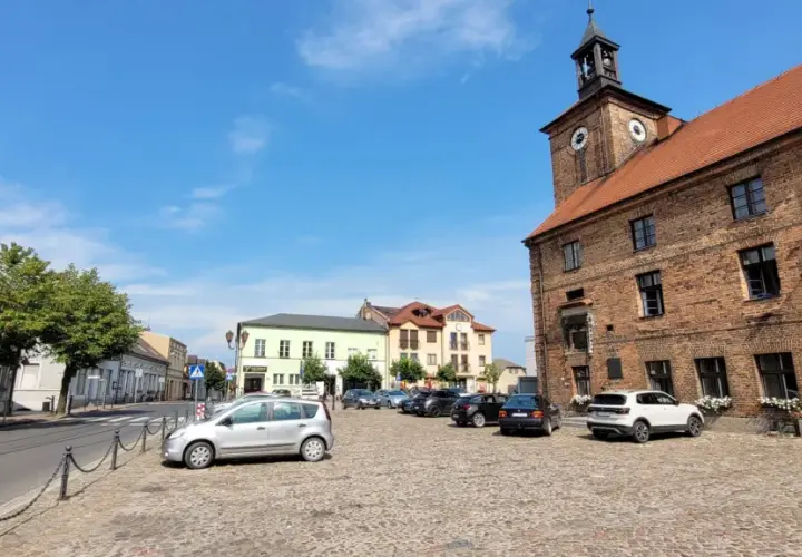 Rynek w Połajewie z ratuszem i kolorowymi kamienicami.