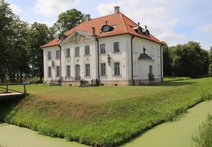 Pałac w Choroszczy otoczony fosą i zielenią. Drewniany mostek prowadzi do rezydencji.