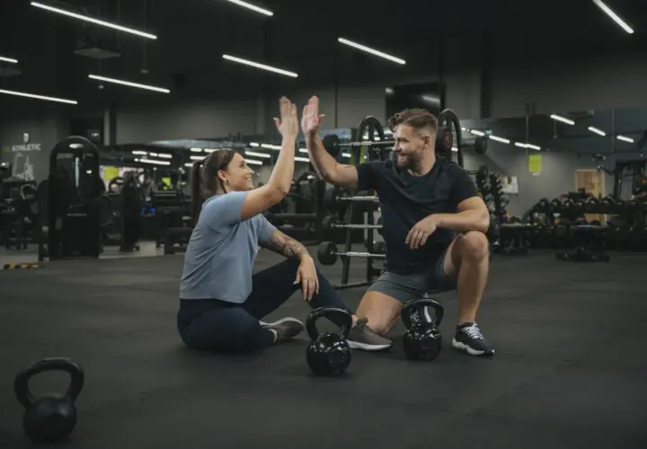 Para, którzy szukają crossfit Wrocław, gdzie można poczuć energię i wsparcie. Para świętuje sukces na siłowni.