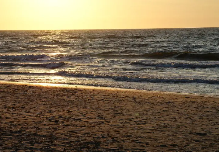 Piękny zachód słońca Sarbinowo. Złote światło odbija się od fal Bałtyku, tworząc magiczny widok na piaszczystej plaży.