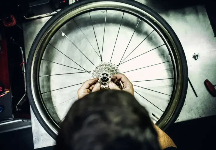 Ręce mechanika składają kasetę z zębatkami, przygotowując wolnobieg do montażu na kole rowerowym.