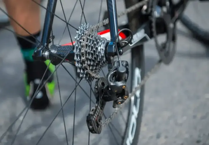 Jak naciągnąć łańcuch w rowerze z przerzutkami Shimano? Widok tylnego koła z kasetą i przerzutką.