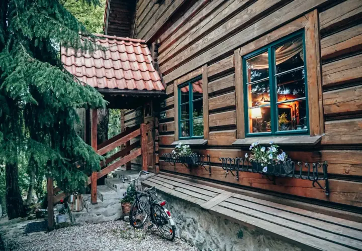 Drewniana chata z kwiatami w oknach i rowerem przy schodach. Idealne romantyczne miejsca Dolny Śląsk na wypoczynek.