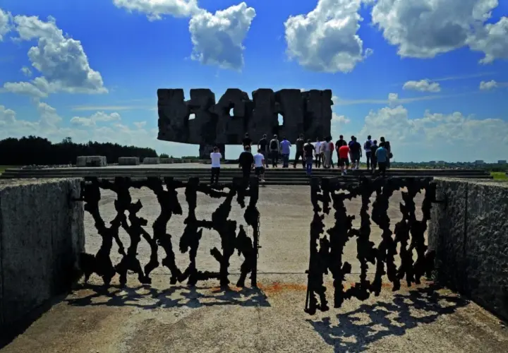 Brama pamięci na terenie byłego obozu Majdanek. Grupa ludzi zwiedza miejsce pamięci.