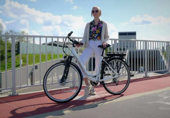 Kobieta z rowerem elektrycznym na moście. Czy na rower elektryczny trzeba mieć prawo jazdy? Zależy od jego mocy.